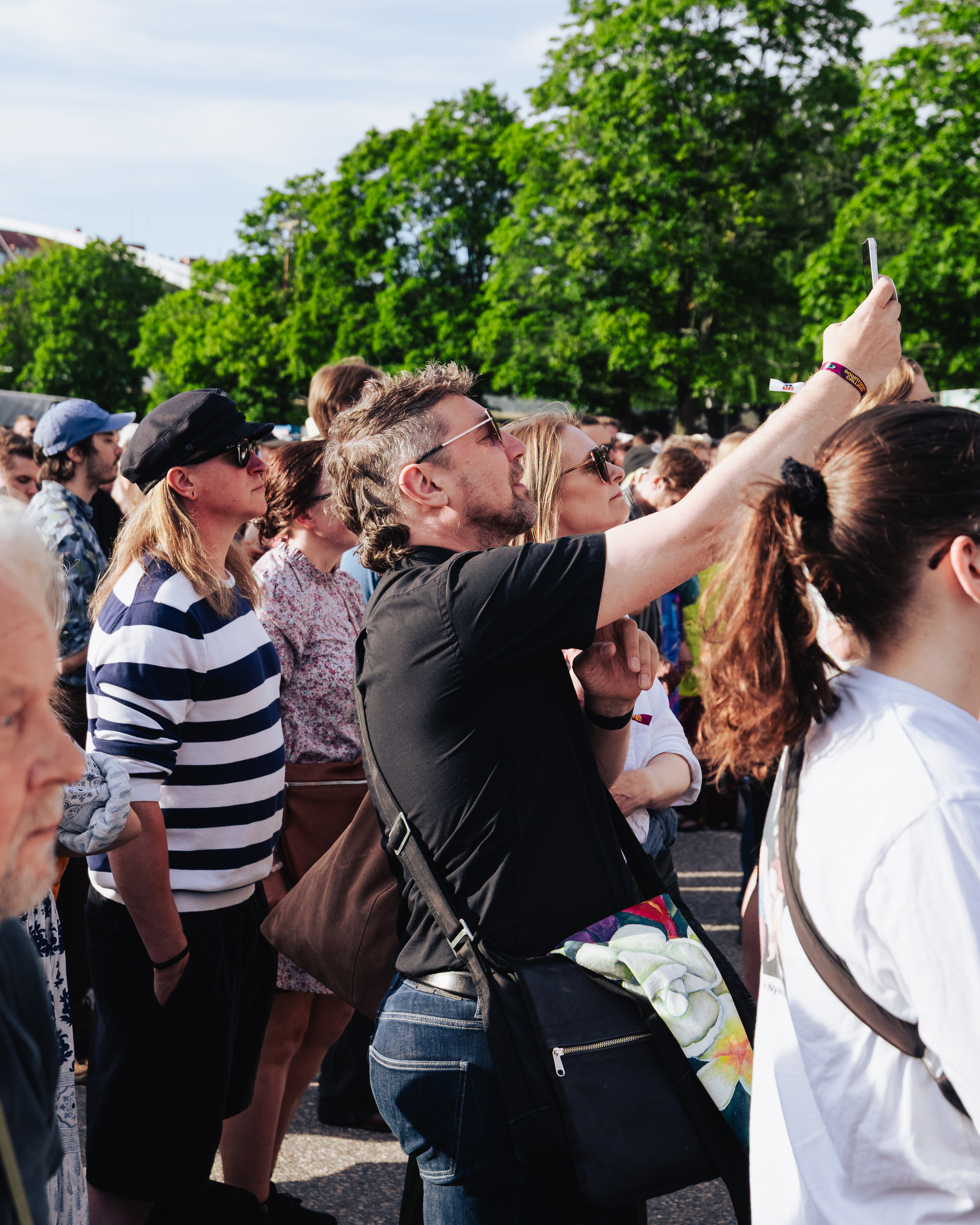 yleisöä tapahtumassa, henkilö kuvaamassa puhelimella